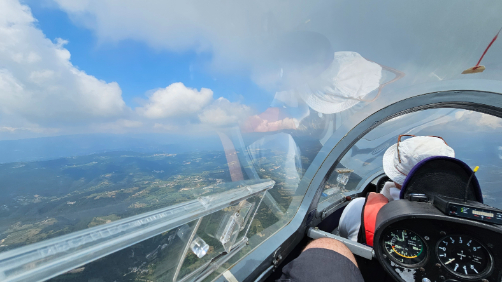 Interno di un aliante durante il volo con vista del copilota e del paesaggio sottostante