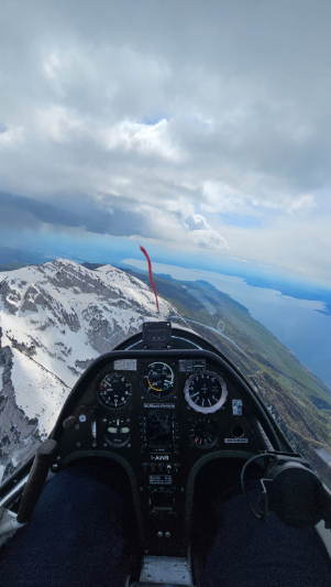 Vista dal cockpit di un aliante sorvolando il Monte Baldo innevato con il Lago di Garda in lontananza