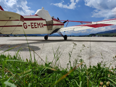 Vista dal basso dell'aereo trainatore parcheggiato ad Asiago con erba in primo piano