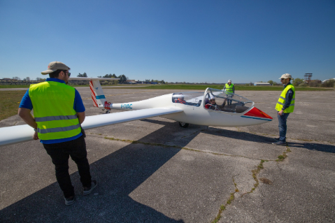 Piloti in giubbotto riflettente accanto a un aliante pronto per il decollo